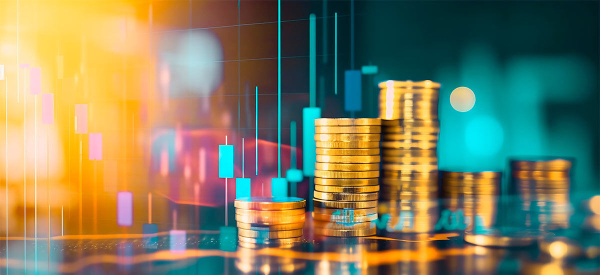 Stacks of coins in front of colorful financial charts as a symbol for costs and profits.